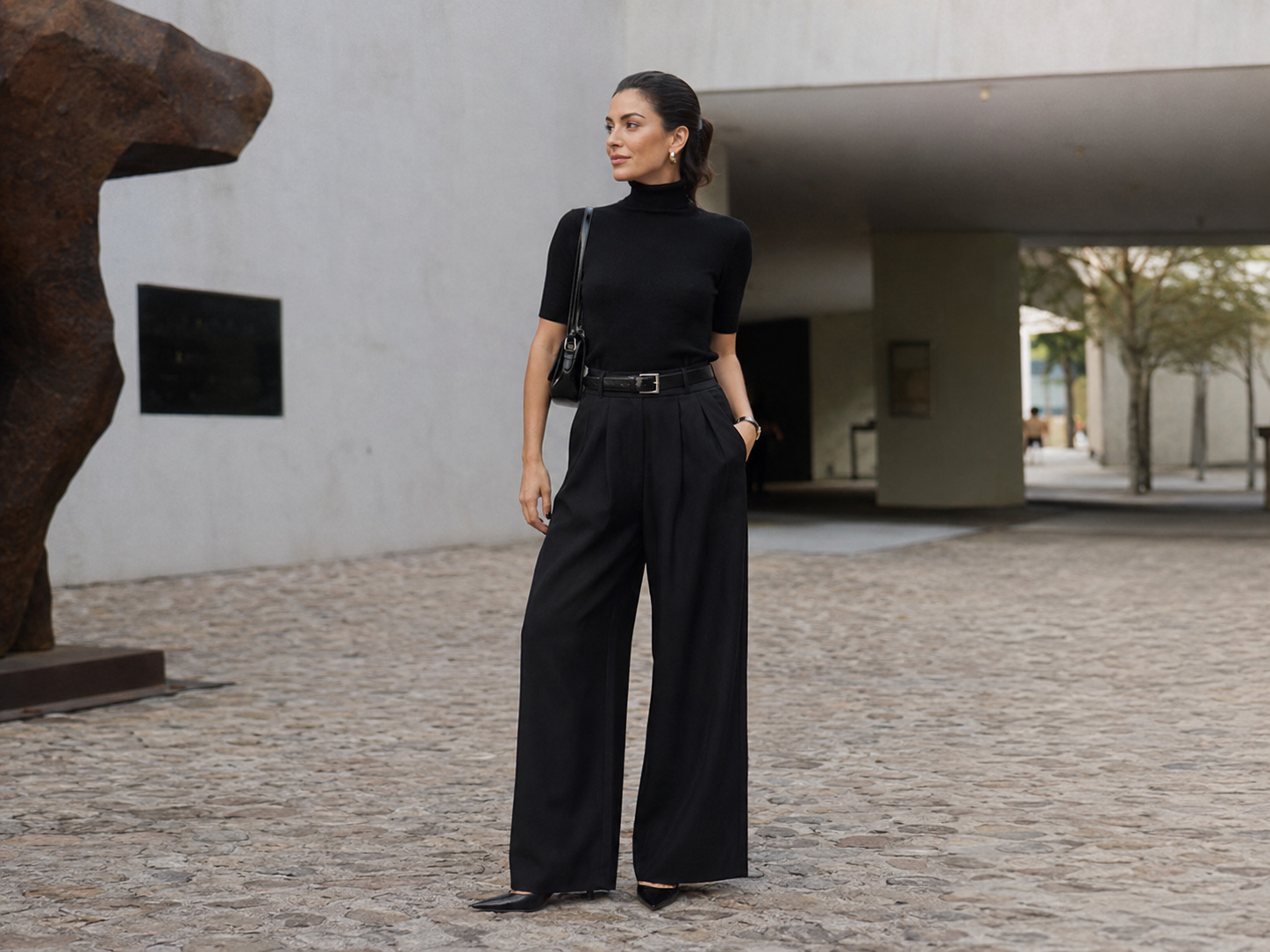 Mulher com blusa ajustada e calça wide leg preta em cenário urbano contemporâneo.
